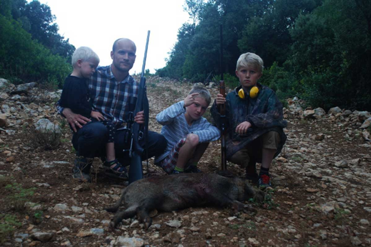 Father and three sons with wild boar on pose